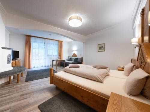 A cozy hotel room with wooden furnishings, soft lighting, and a balcony view offers a serene retreat for travelers seeking comfort and relaxation.