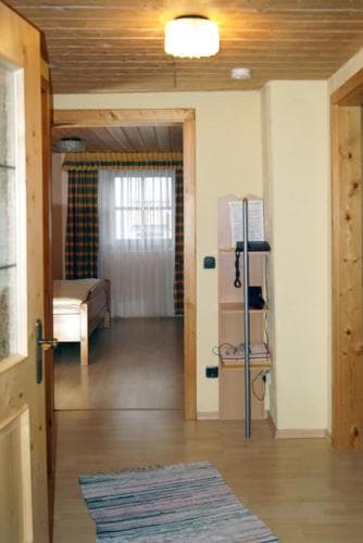 A cozy wooden cabin interior features a warmly lit hallway leading to a bedroom with rustic decor, ideal for travelers seeking a serene mountain retreat experience.
