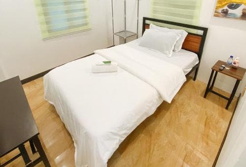 A cozy hotel room with a neatly made bed, wooden flooring, and minimalistic decor offers a serene retreat for travelers seeking simplicity and comfort.