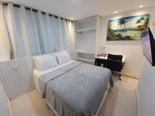 A cozy hotel room features a neatly made bed, a desk with a chair, and a tropical mural, creating a serene atmosphere ideal for travelers seeking comfort and relaxation.