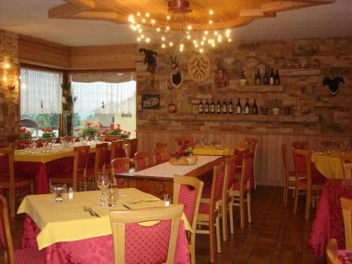 A cozy restaurant with rustic stone walls, wooden furniture, and vibrant tablecloths creates a warm and inviting atmosphere, perfect for travelers seeking a charming dining experience.