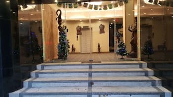 A festive indoor space features a staircase leading to a warmly lit area adorned with Christmas trees and cultural sculptures, creating an inviting atmosphere ideal for holiday-themed events or cultural tours.