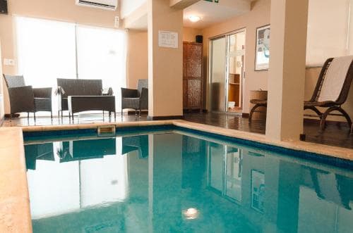 A serene indoor pool area with lounge chairs and a cozy seating nook offers a relaxing retreat for travelers seeking leisure and comfort.