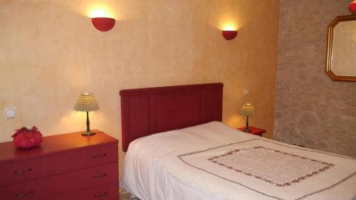 A cozy bedroom with warm-toned walls, red accents, and soft lighting creates an inviting atmosphere, perfect for travelers seeking a comfortable and intimate accommodation experience.
