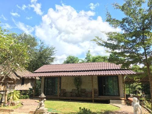A serene tropical bungalow surrounded by lush greenery under a bright blue sky, ideal for a peaceful retreat and perfect for travelers seeking relaxation in nature.