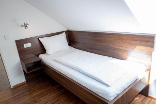 A cozy attic bedroom with a sleek wooden bed and matching bedside table bathed in soft natural light, ideal for travelers seeking a serene and modern accommodation experience.