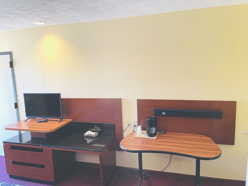 A cozy hotel room corner features a wooden desk setup with a TV and coffee maker, ideal for travelers seeking comfort and convenience during their stay.