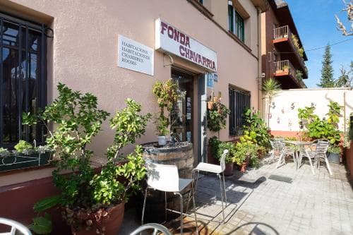 A cozy outdoor seating area adorned with potted plants and tables invites travelers to relax at Fonda Chavarria, an inviting eatery with rustic charm perfect for a leisurely dining experience.