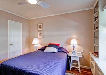 A cozy bedroom with a neatly made bed, soft lighting from bedside lamps, and a tidy desk exudes comfort, ideal for travelers seeking a peaceful retreat.