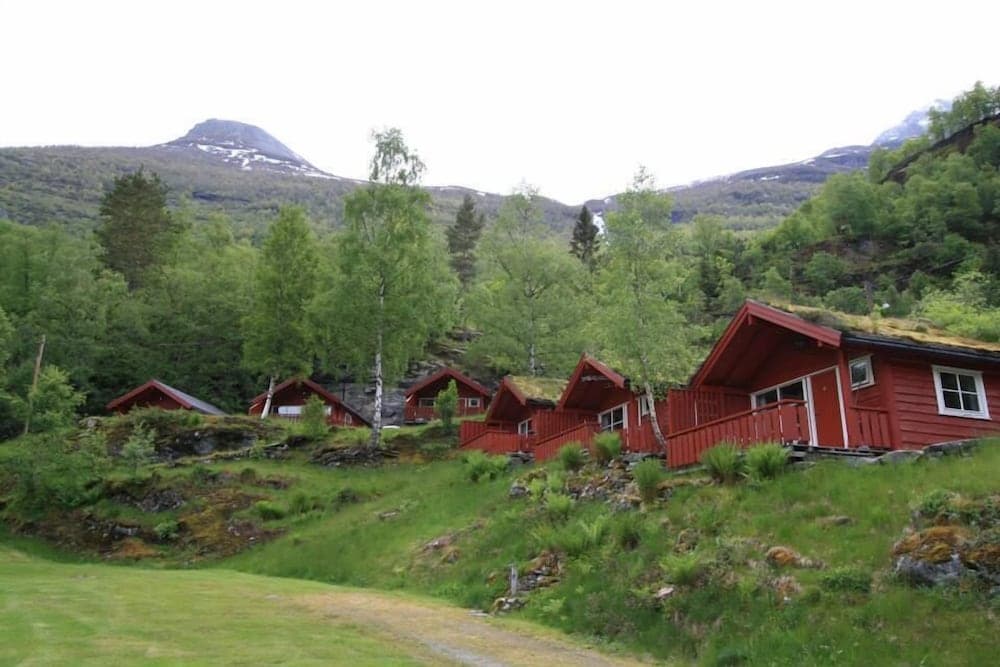 A serene mountain retreat features charming red cabins nestled among lush greenery, ideal for travelers seeking a peaceful getaway in nature.