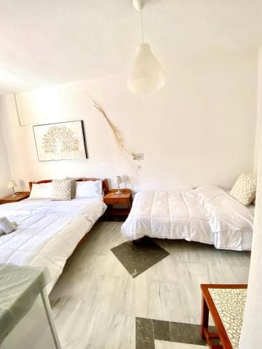 A cozy, minimalist bedroom with two neatly made beds, soft lighting, and modern decor creates a serene atmosphere ideal for travelers seeking a peaceful retreat.
