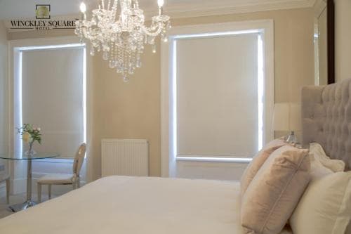 A cozy hotel room features a plush bed, elegant chandelier, and soft lighting, creating a serene atmosphere ideal for relaxation and leisure travel.