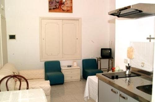 A cozy studio apartment featuring a compact kitchenette, comfortable seating, and vintage decor, ideal for travelers seeking a quaint and functional stay in an urban setting.
