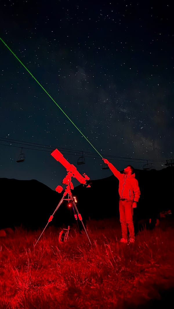 Stargazing tour guide pointing out stars beside a telescope under a dark sky