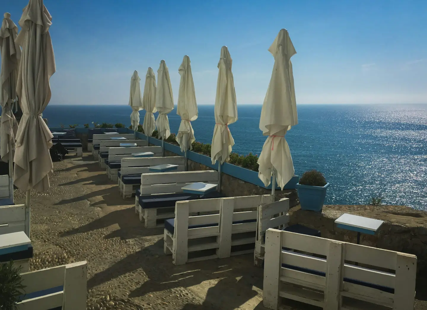 Café tables and parasols on a clifftop above the sea