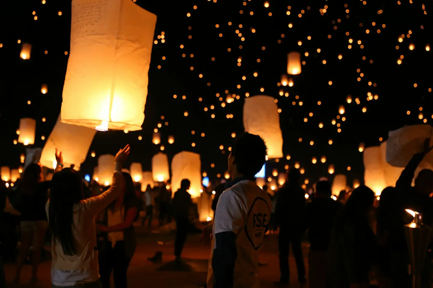 Crowds releasing paper lanterns into the night sky