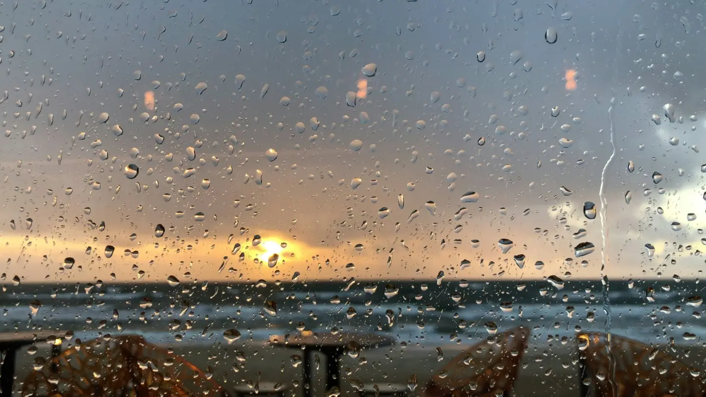 Raindrops on a window looking out over a grey beach
